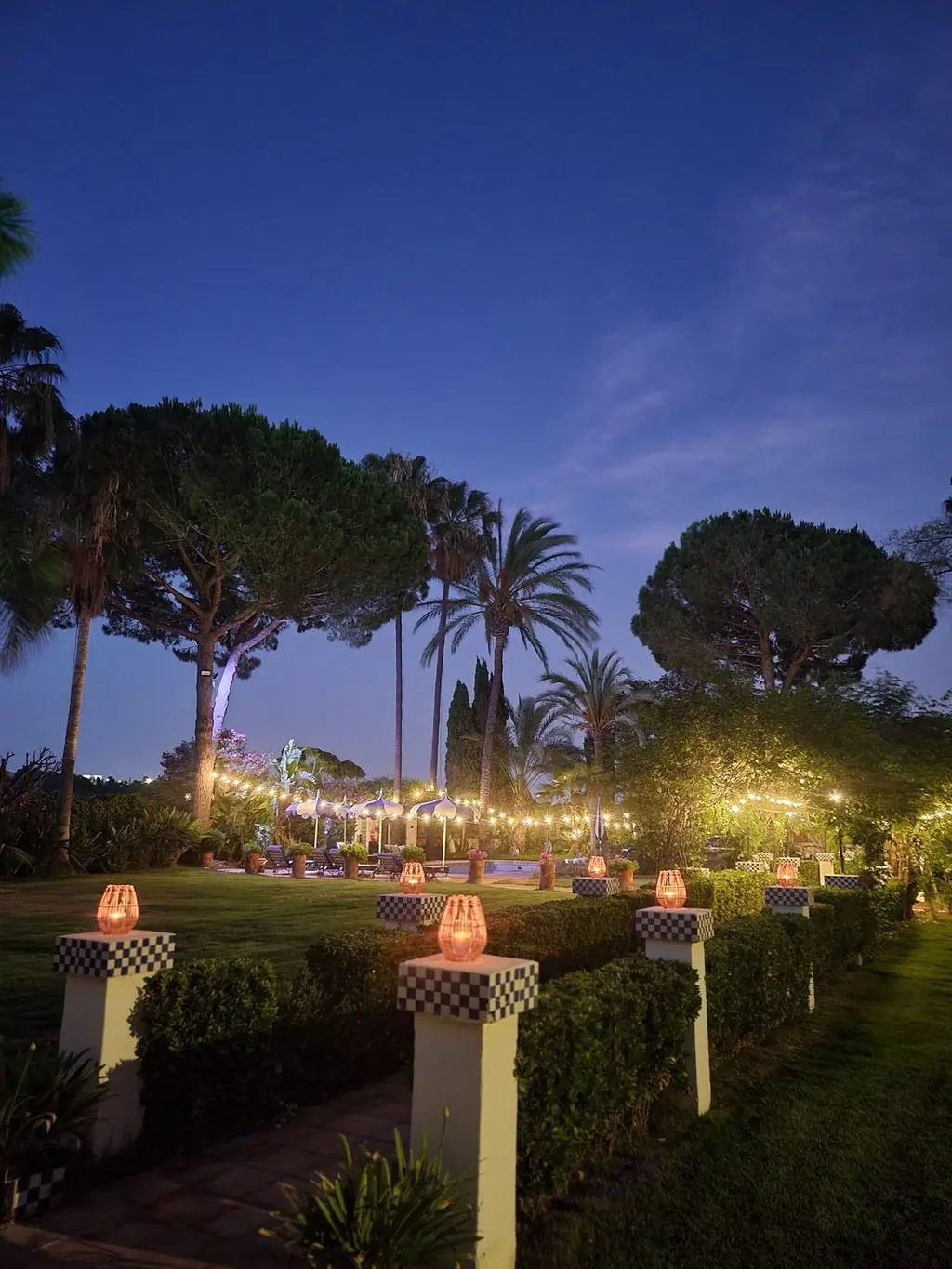 Paseo del jardín de Villa Paula iluminado con faroles al anochecer