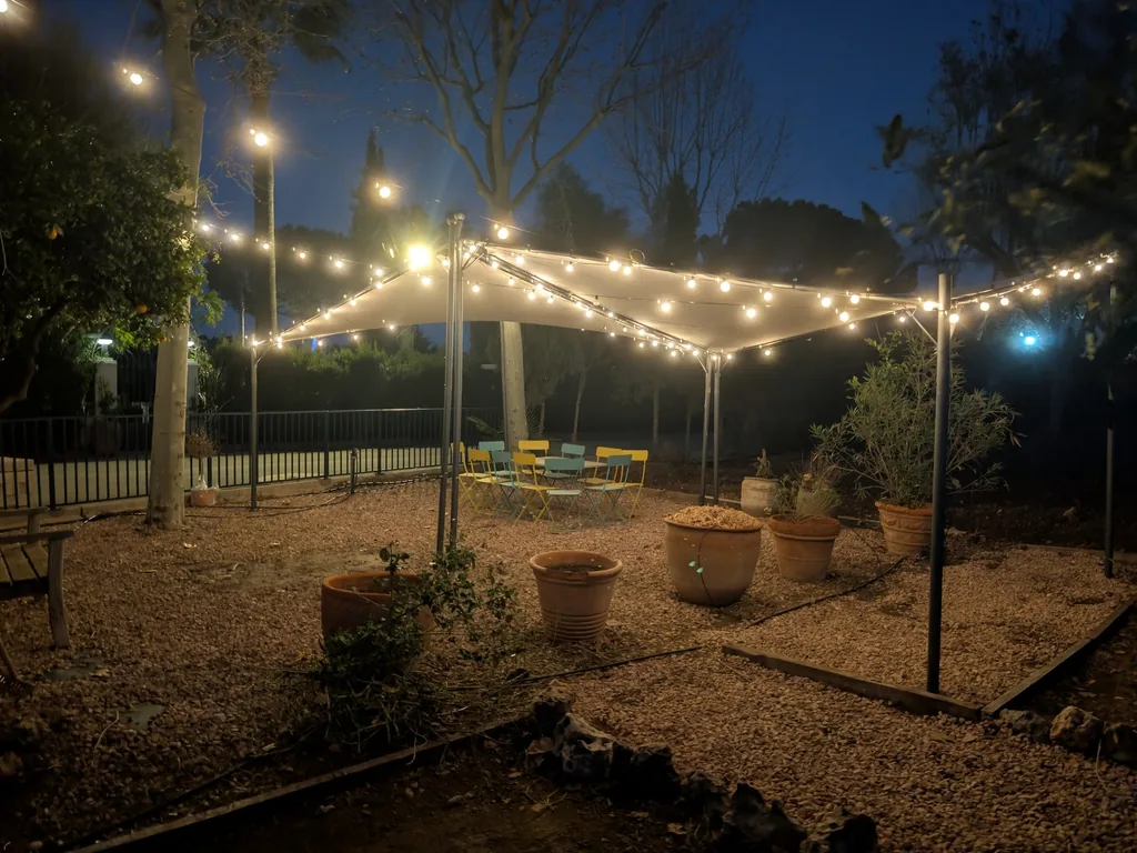 Tafel onder de gazebo in de moestuin van Villa Paula, ’s nachts verlicht