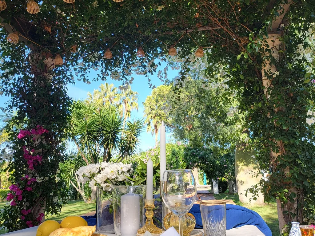 Tafel onder de pergola van witte bougainville in de tuin van Villa Paula