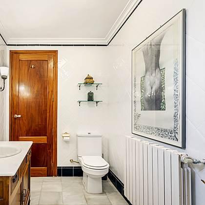 Ba&ntilde;o de Villa Paula con tocador de madera antiguo y un cuadro fotogr&aacute;fico en blanco y negro sobre el radiador