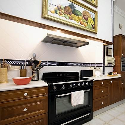 Cocina de Villa Paula con horno de gama SMEG, azulejos con mural de frutas y armarios de madera