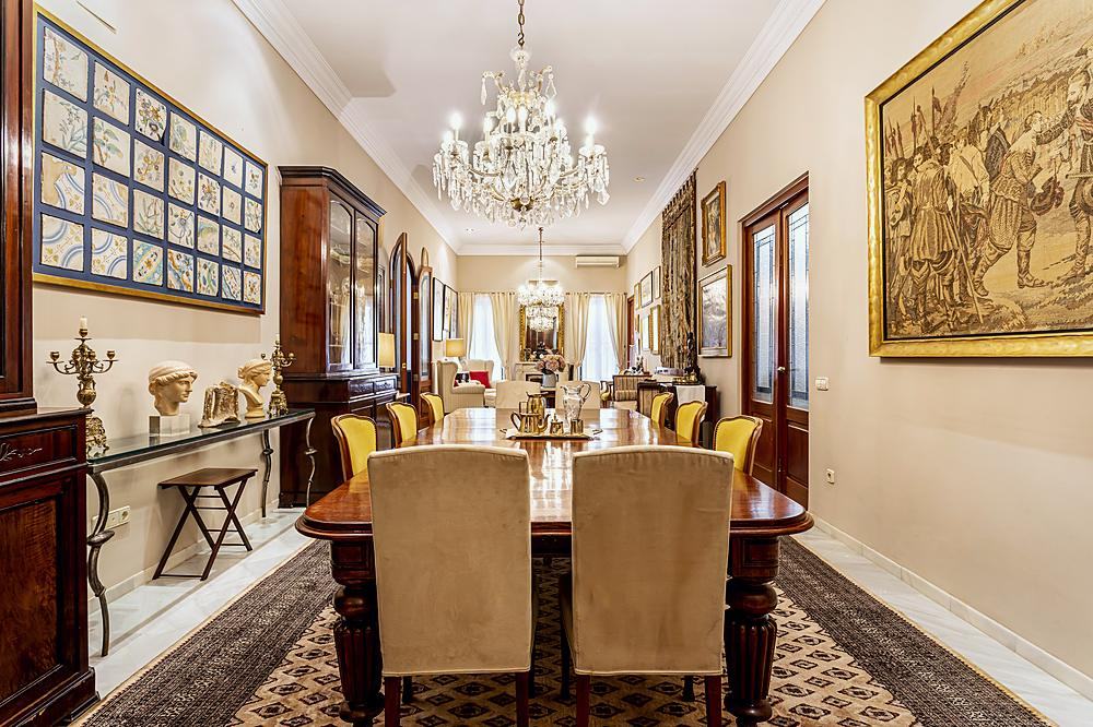 Comedor de Villa Paula con l&aacute;mpara de ara&ntilde;a, tapiz enmarcado y az&uacute;lejos antiguos en la pared