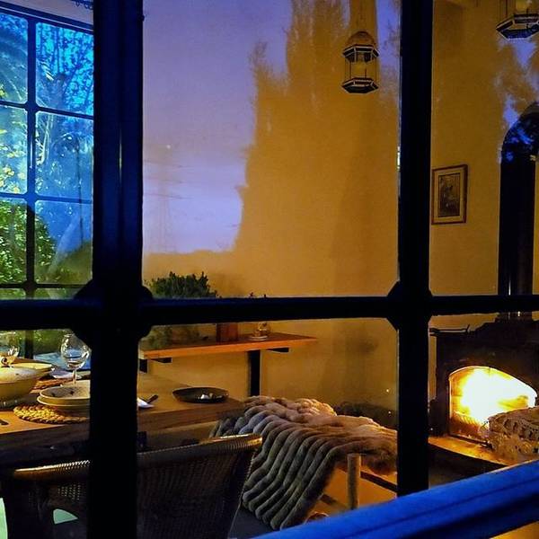 Vista nocturna de Villa Paula con la mesa puesta y la chimenea encendida