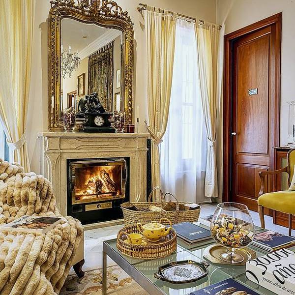 Sal&oacute;n de Villa Paula con espejo dorado y chimenea encendida
