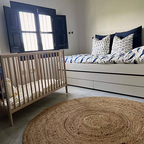 Habitaci&oacute;n de los ni&ntilde;os en Villa Paula, con cuna, cama y ropa de cama de ballenas junto a la ventana de postigos azules