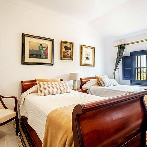 Habitaci&oacute;n Taurino de Villa Paula, en tonos borgo&ntilde;a con grabados taurinos en la pared