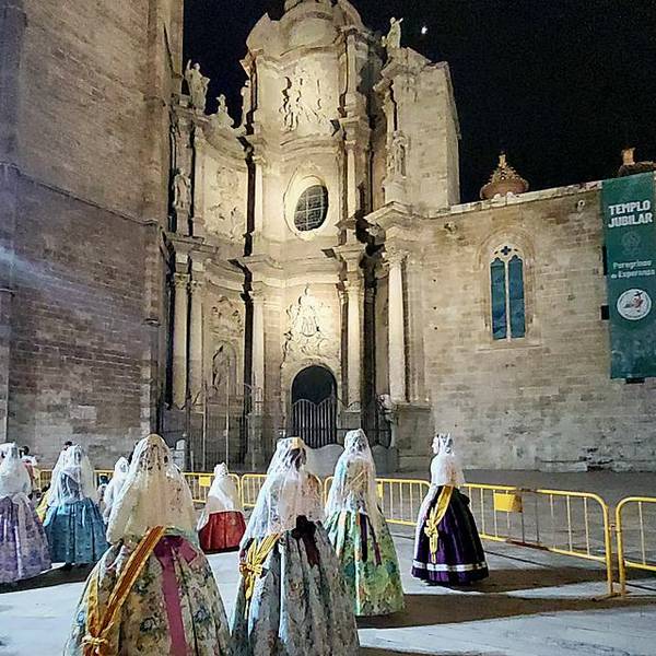 Falleras frente a la Catedral de Valencia iluminada de noche