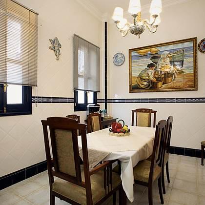 Rinc&oacute;n del desayuno en Villa Paula con l&aacute;mpara de ara&ntilde;a, azulejo pintado a mano y la mesa puesta para el grupo