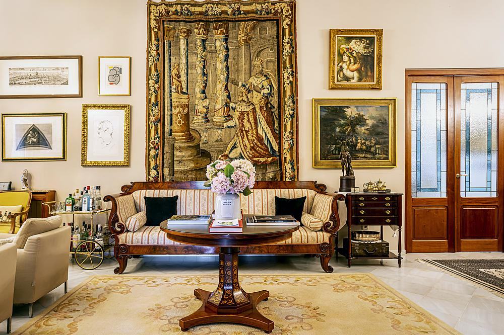 Tapiz antiguo y galer&iacute;a de cuadros sobre un sof&aacute; isabelino en un sal&oacute;n de Villa Paula